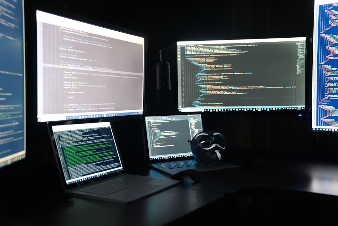 Software developer coding at computer with multiple screens showing code
